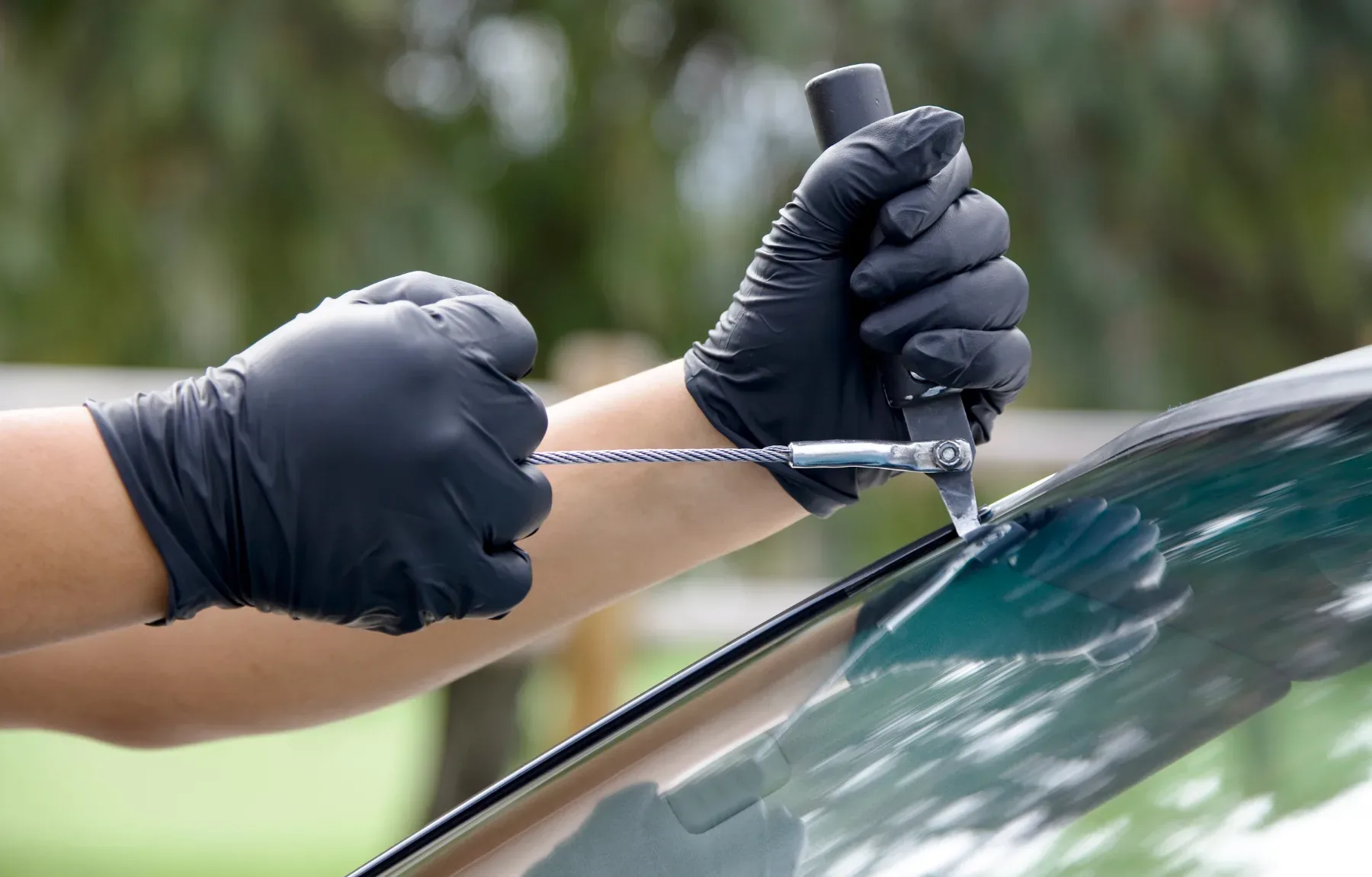Technician holding auto glass repair tool near vehicle windshield